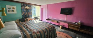 A hotel room with a bed, a desk, a television, and a window with curtains.