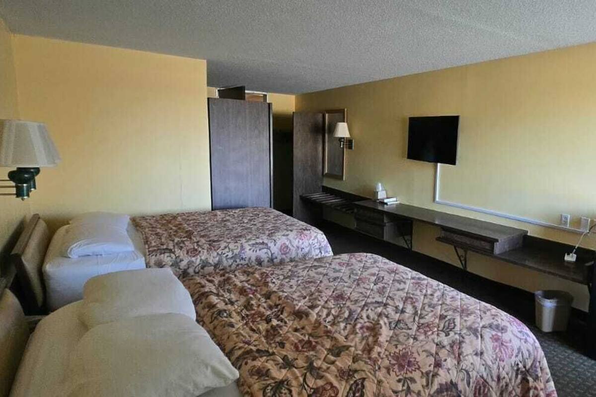 Habitación de hotel con dos camas, un escritorio con computadora, televisión y microondas.