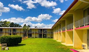 A yellow building with multiple balconies and a green lawn.