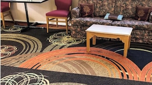 Una habitación con sofá, una mesita, una silla y una alfombra estampada.