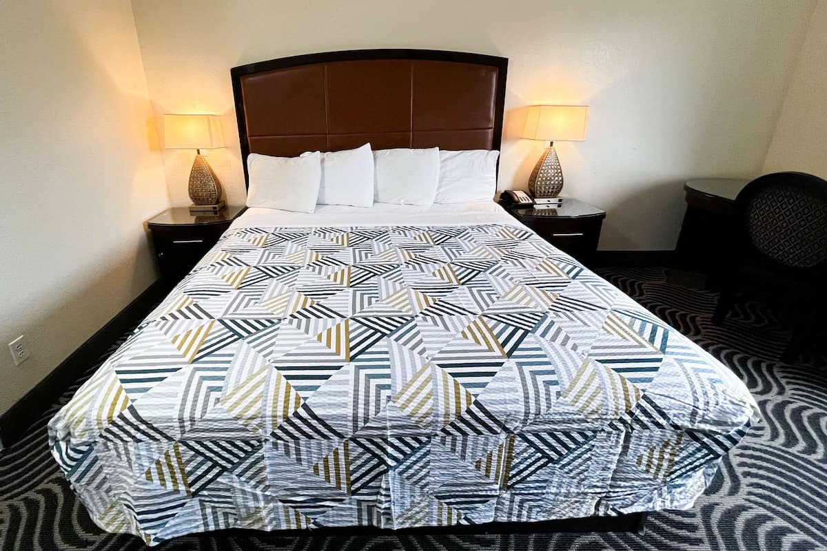 Ett hotellrum med en stor säng, två sänglampor och en sänggavel.