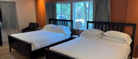 A hotel room with two beds, a desk, and a chair.