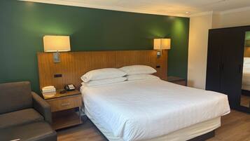 Une chambre d’hôtel comprenant un lit, des lampes de chevet, un téléphone, un bureau et une armoire.