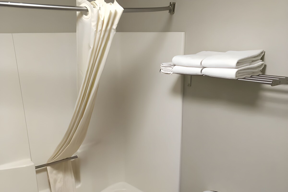 Un baño con bañera, inodoro y toallero con toallas dobladas.