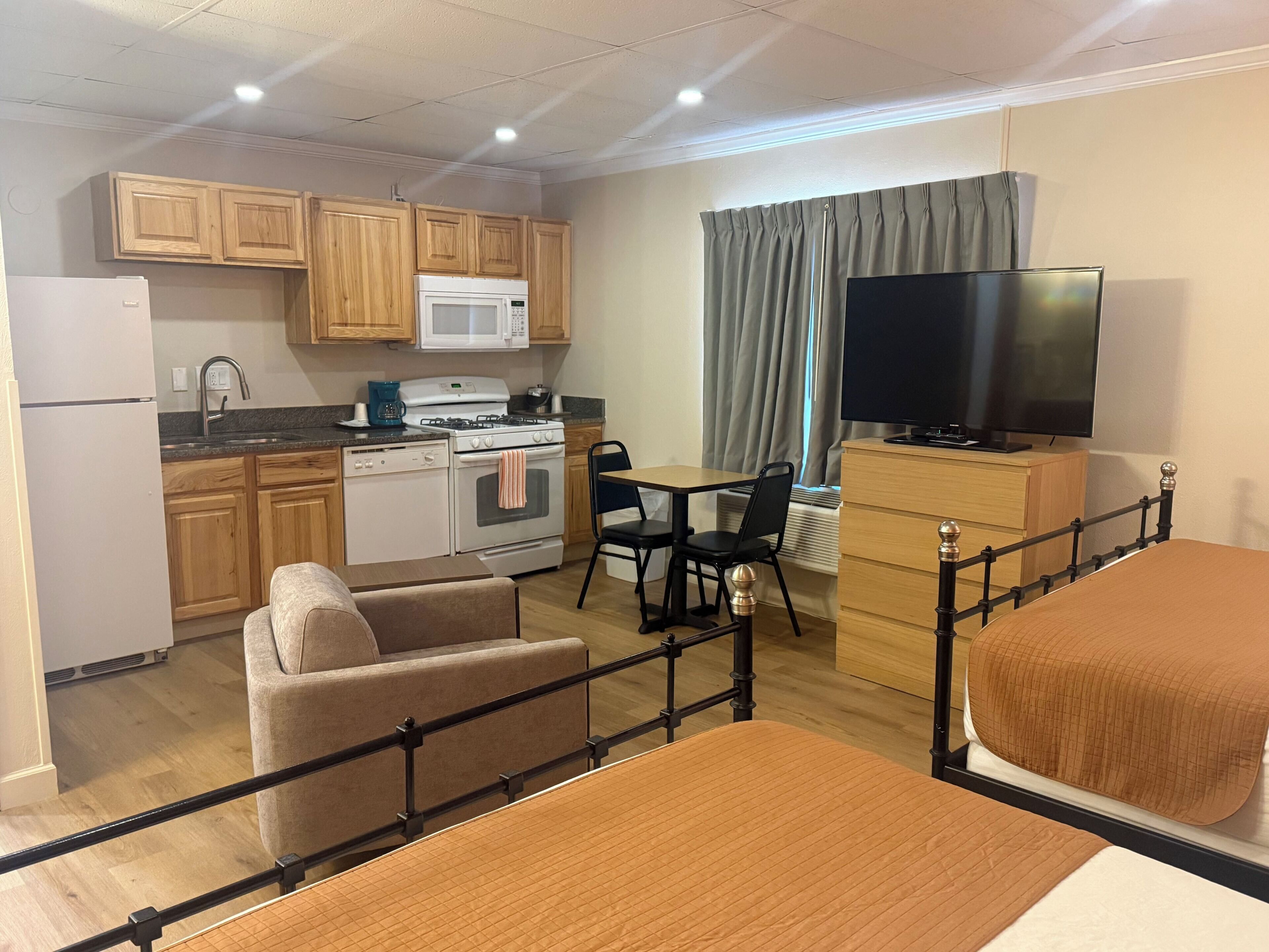 Una habitación de hotel compacta con kitchenette, comedor, televisión y cama.