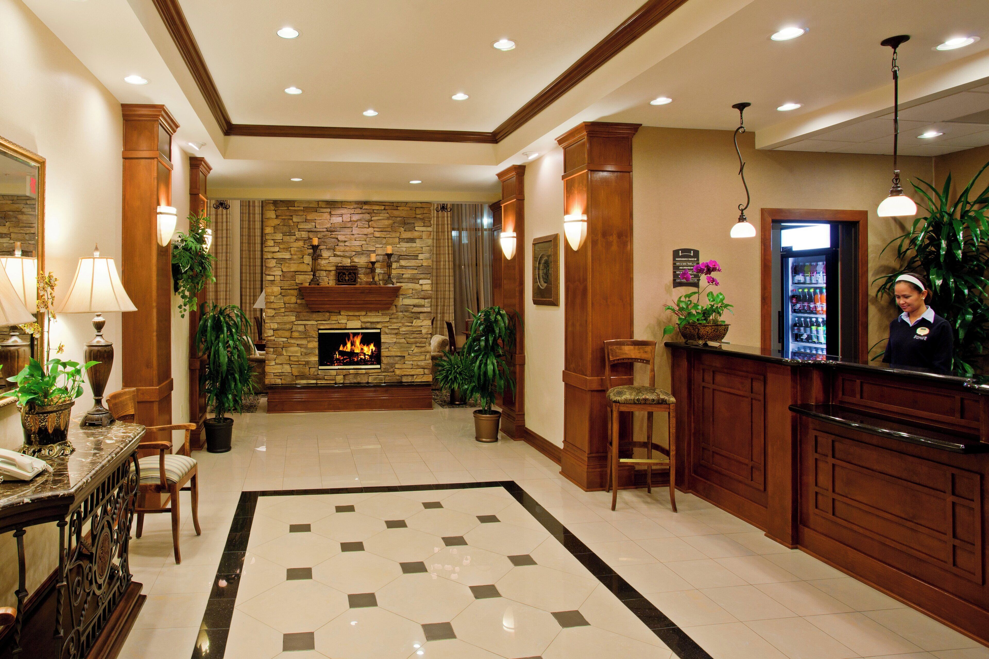 Um hall de hotel com lareira de pedra, balcão de recepção e chão de azulejos.