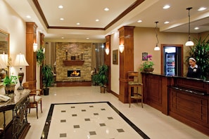 A hotel lobby with a stone fireplace, a reception desk, and a tiled floor. - Staybridge Suites Lake Forest by IHG (Foothill Ranch)