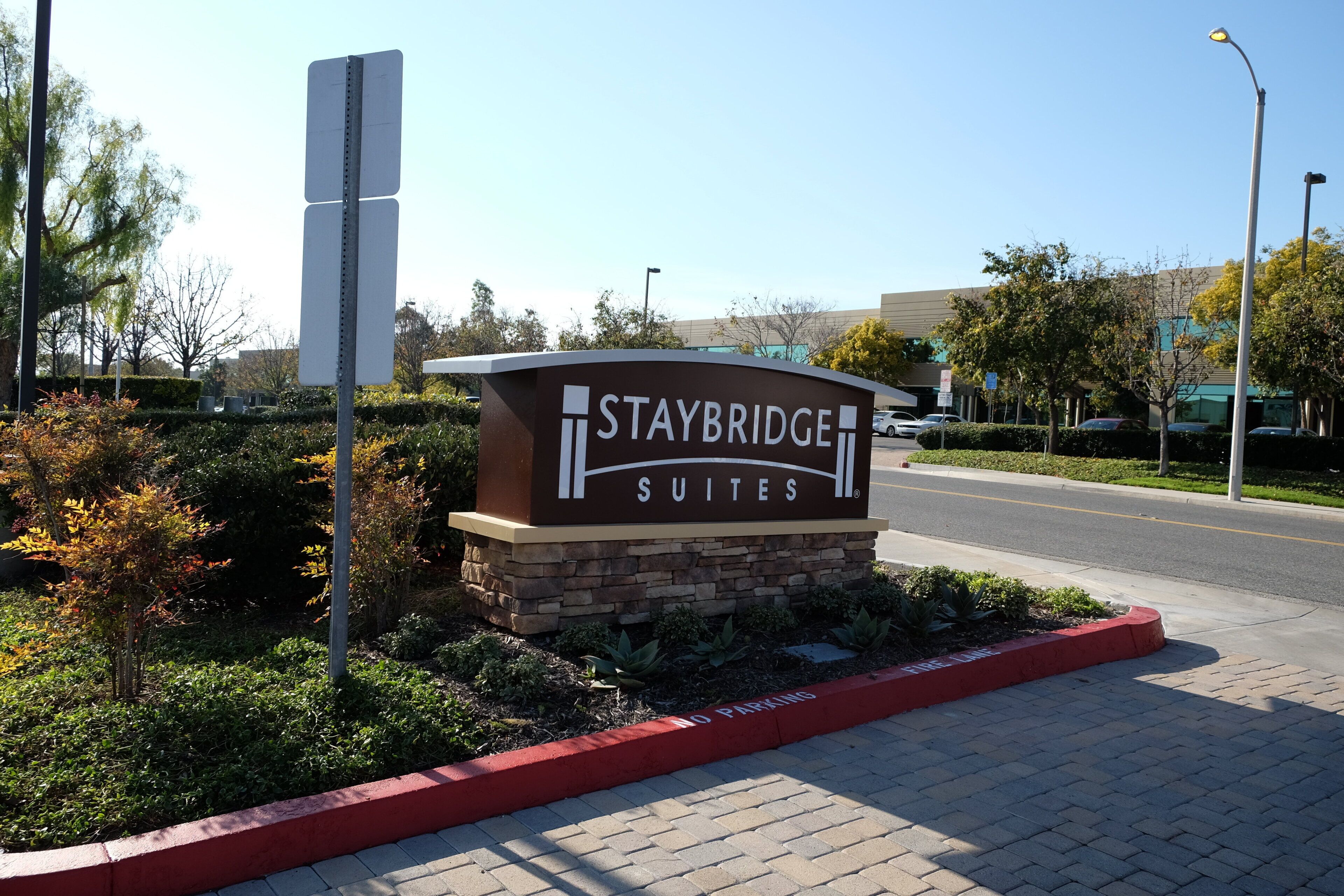Señal de Staybridge Suites, con una vista despejada del estacionamiento y una carretera al fondo.