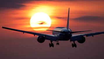 An airplane flying with a sunset in the background.
