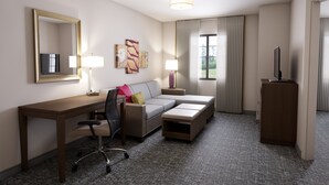 A hotel room with a desk, a sofa, a TV, and a cabinet. - Staybridge Suites Lake Forest by IHG (Foothill Ranch)
