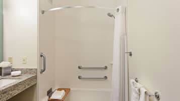 Un baño con ducha, barras de apoyo, toallero y lavabo con encimera de mármol.