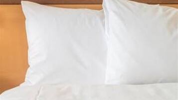 A bed with white bedding and a wooden headboard.