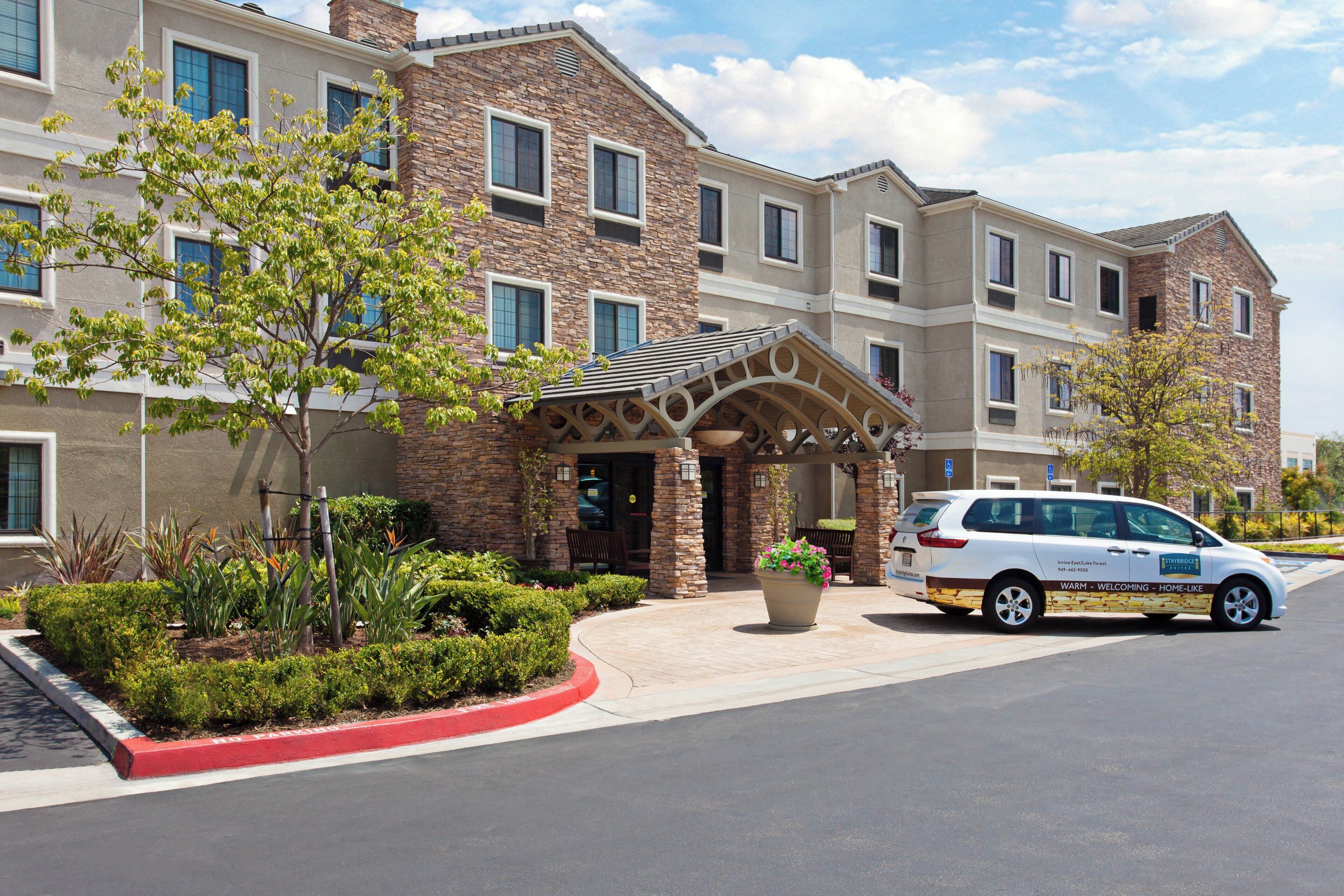 A multi-story hotel with a stone facade, a covered entrance, and a parking area.