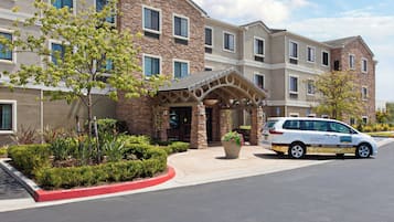 A multi-story hotel with a stone facade, a covered entrance, and a parking area.