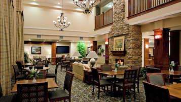 A spacious lobby with a high ceiling, a stone fireplace, multiple seating areas, and a chandelier.