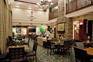A spacious lobby with a high ceiling, a stone fireplace, multiple seating areas, and a chandelier. - Staybridge Suites Lake Forest by IHG (Foothill Ranch)