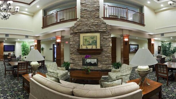 A spacious lobby with a stone fireplace, comfortable seating, and a balcony. - Staybridge Suites Lake Forest by IHG (Foothill Ranch)