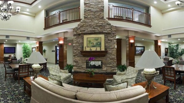 A spacious lobby with a stone fireplace, comfortable seating, and a balcony. - Staybridge Suites Lake Forest by IHG (Foothill Ranch)