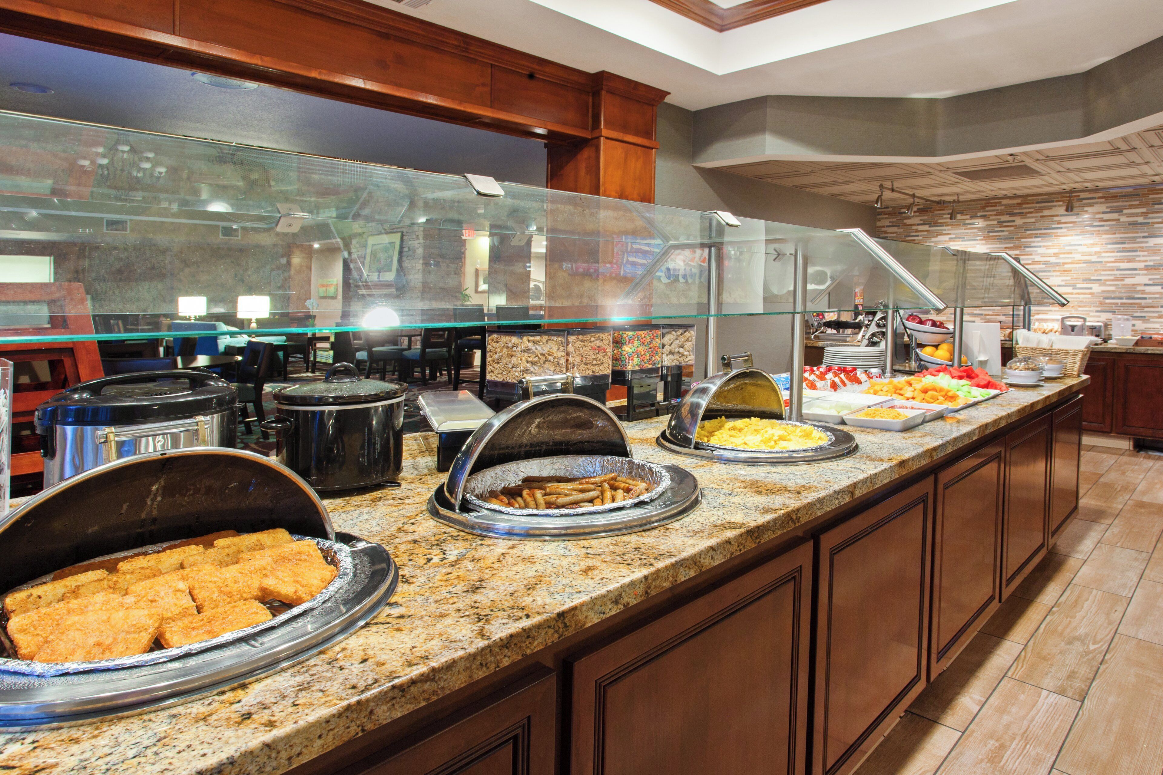 A buffet area with various food options and a seating area in the background.