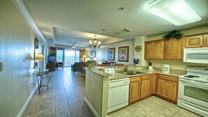 A spacious kitchen with wooden cabinets, a dishwasher, and a stove. There is a dining area with a table and chairs in the background. - Blue Heron Beach Resort (Orlando)
