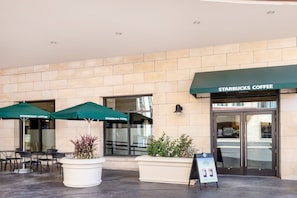 A Starbucks Coffee storefront with outdoor seating and planters.