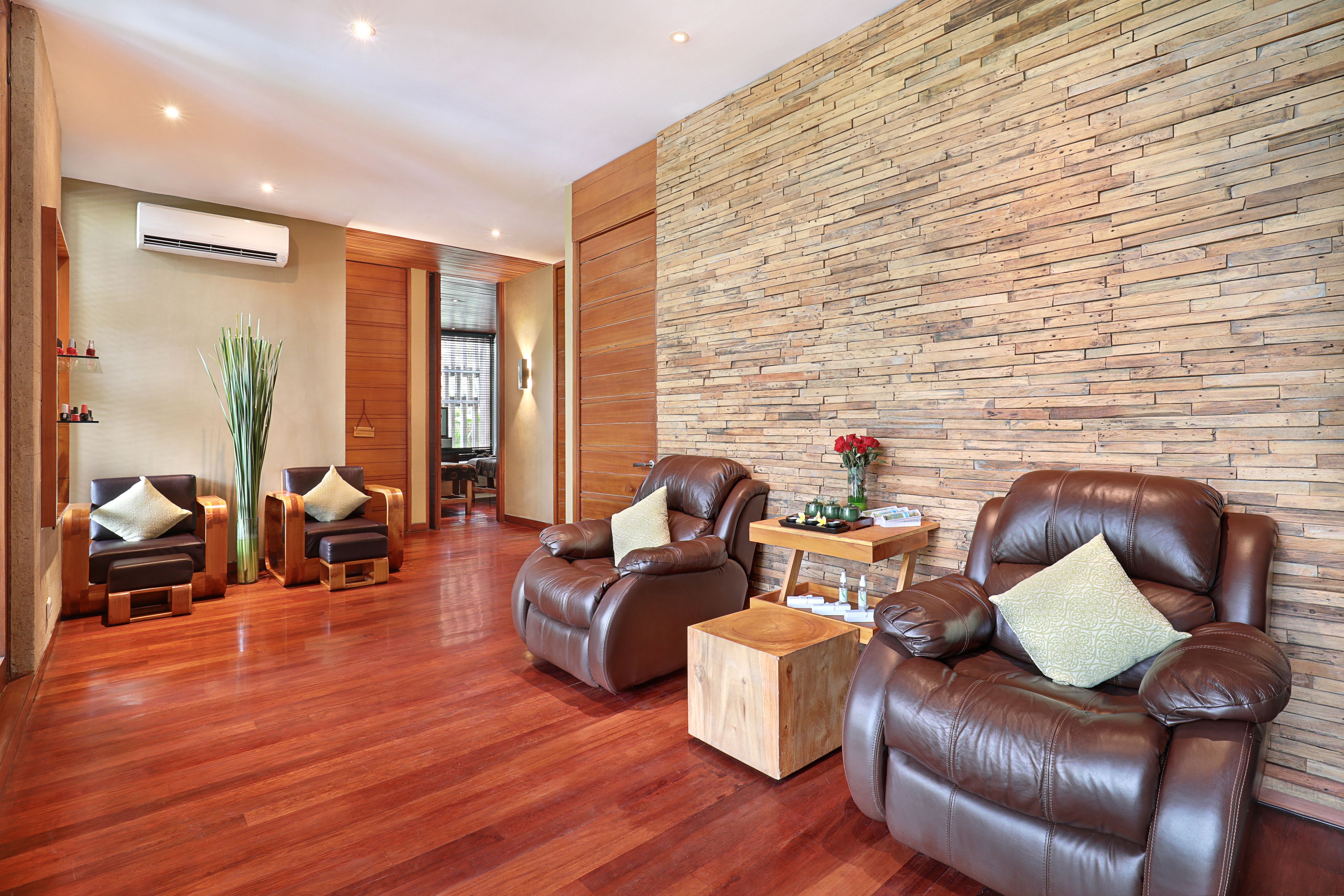 A modern lounge area with leather sofas, a wooden coffee table, and a stone wall.