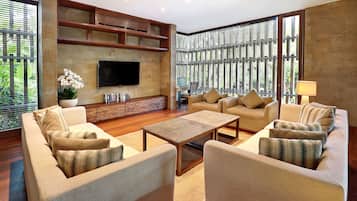 A modern living room with a flat-screen TV, comfortable seating, a coffee table, and a bookshelf.