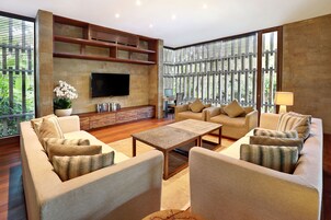 A modern living room with a flat-screen TV, comfortable seating, a coffee table, and a bookshelf.