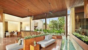 A spacious lobby with a wooden ceiling, a reception desk, seating area, and a view of the outdoors. - The Elysian Boutique Villa Hotel (Seminyak)
