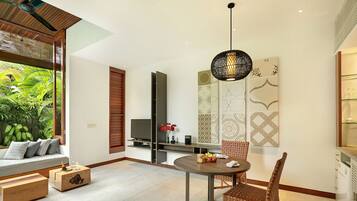 A modern living room with a dining area, a TV, and a view of greenery.