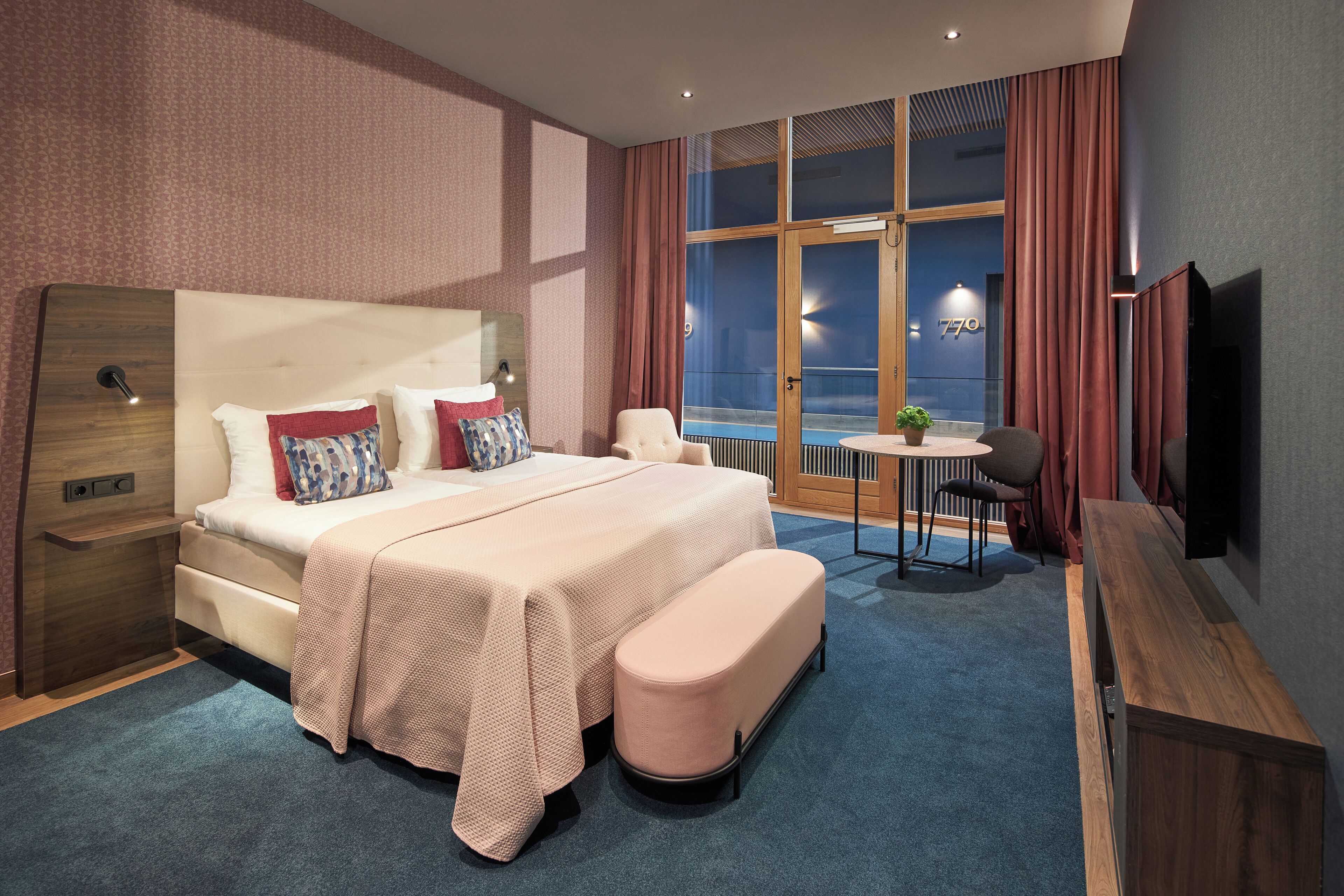 Habitación de hotel moderna con una cama grande, un escritorio, una silla y un televisor.