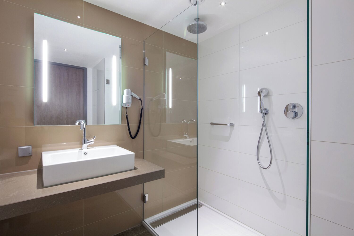 Een moderne badkamer met een grote spiegel, een wastafel en een douchegedeelte.