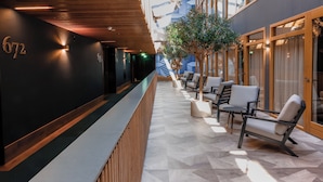 A modern hotel lobby with a reception desk, seating area, and a staircase leading to upper floors. - Van der Valk Hotel Haarlem (Haarlem)