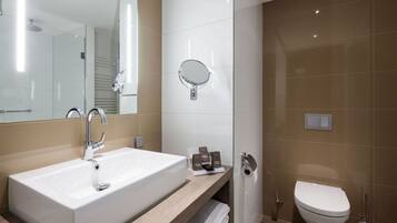 A modern bathroom with a large sink, a mirror, a toilet, and a towel rack.