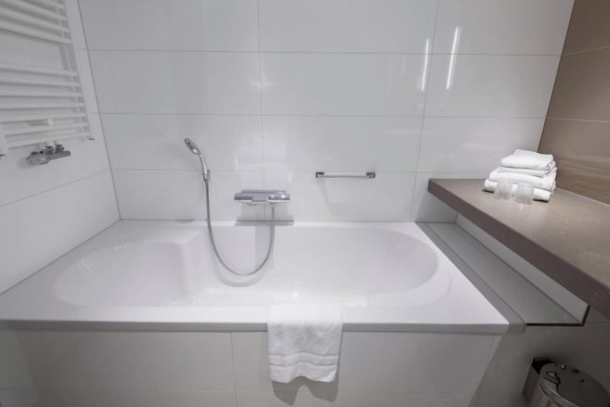 Un baño moderno con bañera, ducha de mano y barra para toallas.