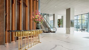 A spacious lobby with marble flooring, a gold reception desk, and a large vase of flowers. - Van der Valk Hotel Haarlem (Haarlem)