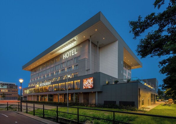 A modern hotel with a restaurant on the ground floor, featuring a prominent 'HOTEL' sign and a large digital display.