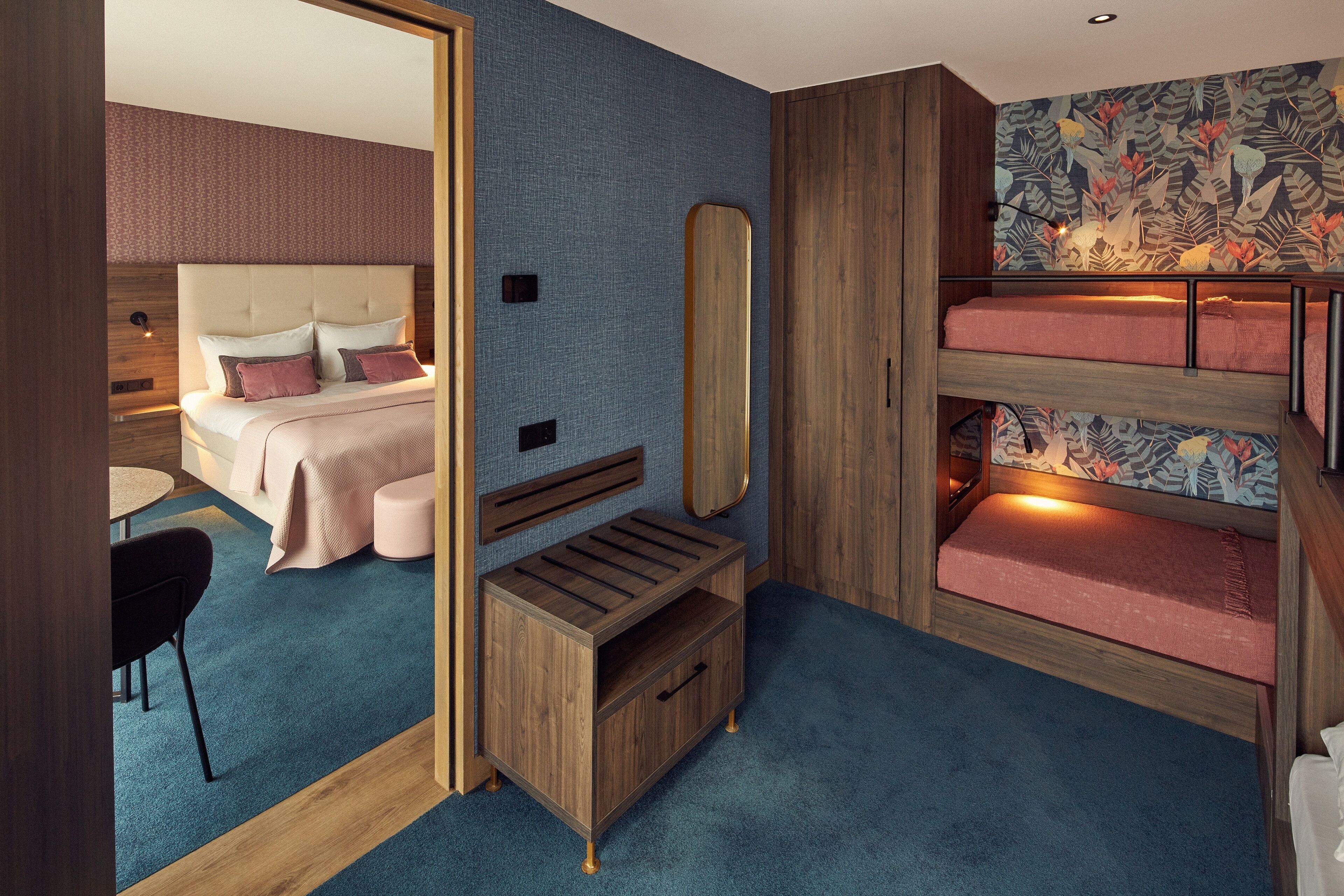 A bedroom with a bed, a bedside table, a mirror, and a bunk bed.