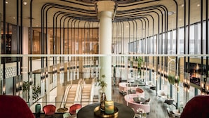 A spacious lobby with a central staircase, modern seating areas, and large windows providing natural light. - Van der Valk Hotel Haarlem (Haarlem)