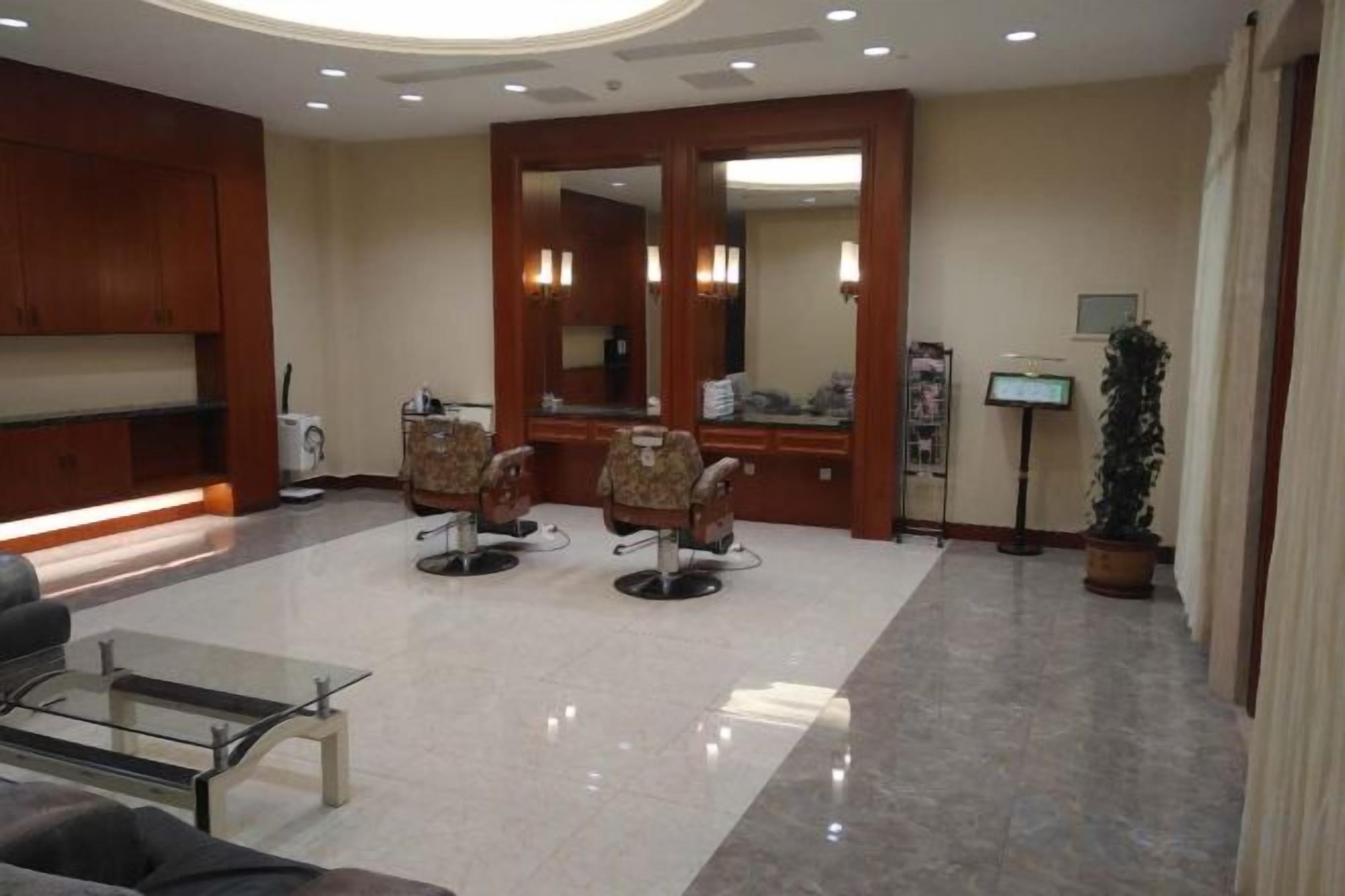 Un hall de hotel con mostrador de recepción, zona de estar y un espejo grande.