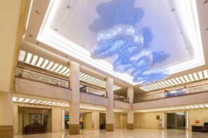 A spacious lobby with a large chandelier, multiple floors, and a polished floor. - South Lake Hotel (CHANGCHUN)