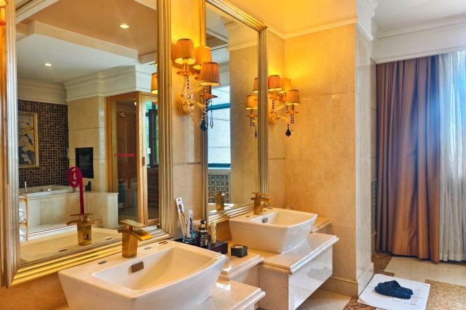 Un baño con dos lavamanos, un espejo grande y apliques de pared.