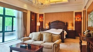 Een slaapkamer met een groot bed, een slaapbank, een kroonluchter en uitzicht op de omgeving.