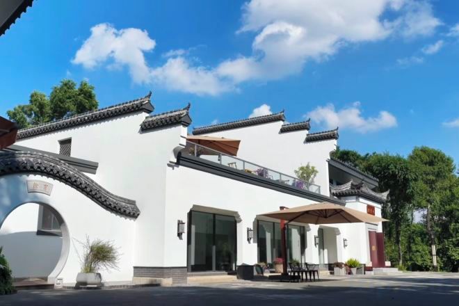 A traditional building with a white facade, a covered entrance, and a balcony.