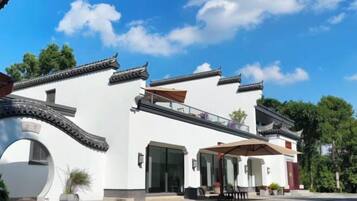 A traditional building with a white facade, a covered entrance, and a balcony.