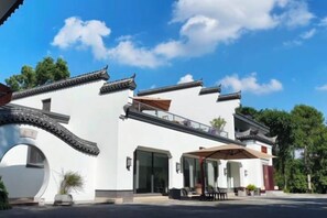 A traditional building with a white facade, a covered entrance, and a balcony.