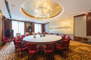 A conference room with a round table, red upholstered chairs, a chandelier, and a patterned carpet. - South Lake Hotel (CHANGCHUN)