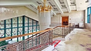 Een statige trap met sierlijke balustrades, een kroonluchter en een kamerbreed tapijt.