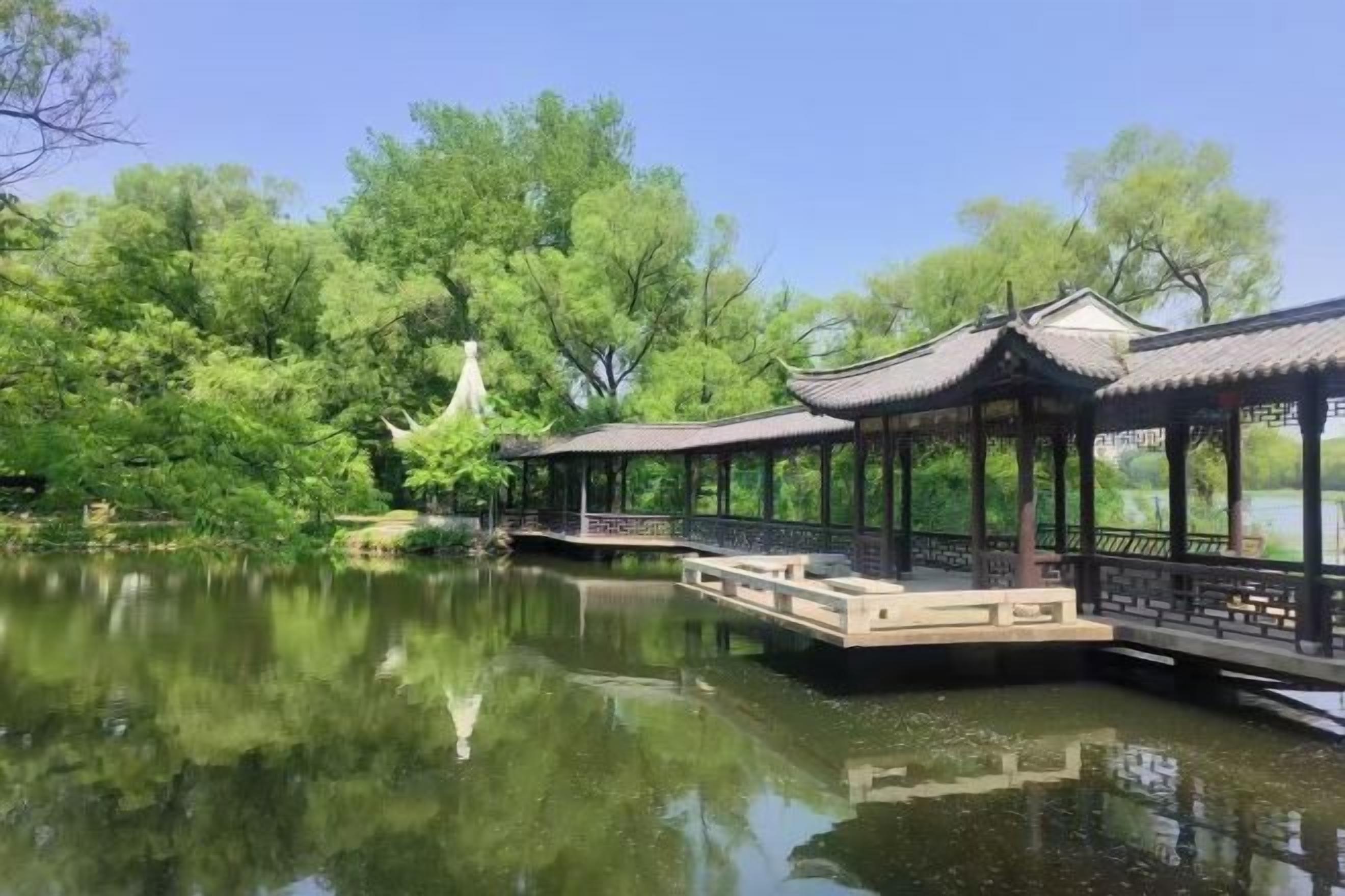 Un padiglione tradizionale in riva a un lago tranquillo con una passerella in legno.
