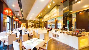 Un restaurante amplio con varias mesas y sillas para comer, una barra central y grandes ventanales que dejan entrar luz natural.